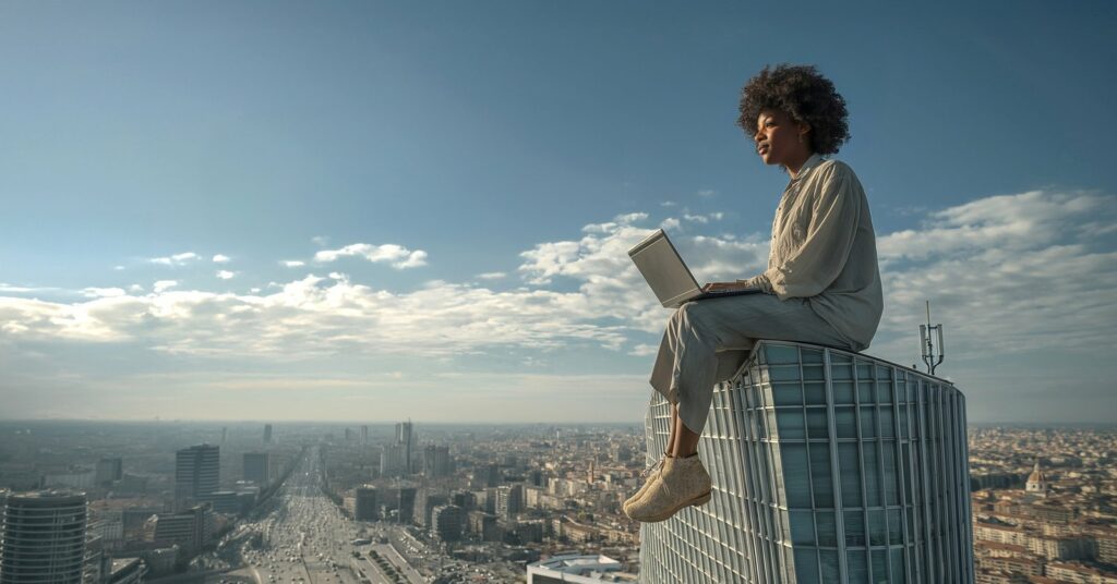 Person with laptop representing cloud infrastructure solutions above a city skyline